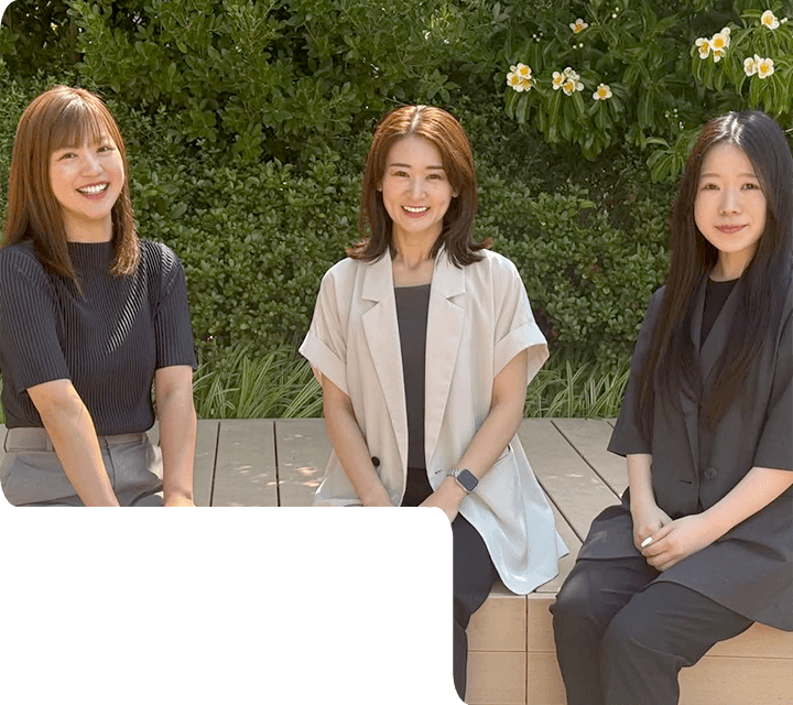 株式会社フォーユーのスタッフ3名が屋外で並んで座っている様子